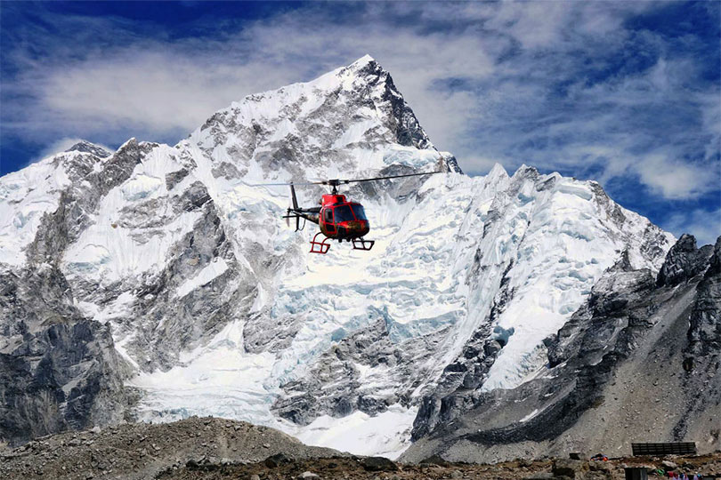 Helicopter passing through the mountains during Nepal Trekking and Everest Himalayan Heli Tour; one of the top luxury tours in Nepal