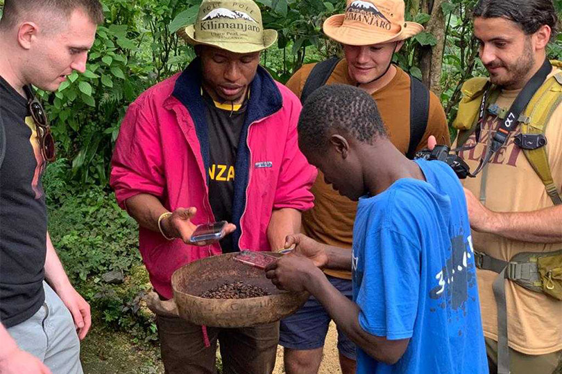Tourists learning coffee making with natives of Tanzania